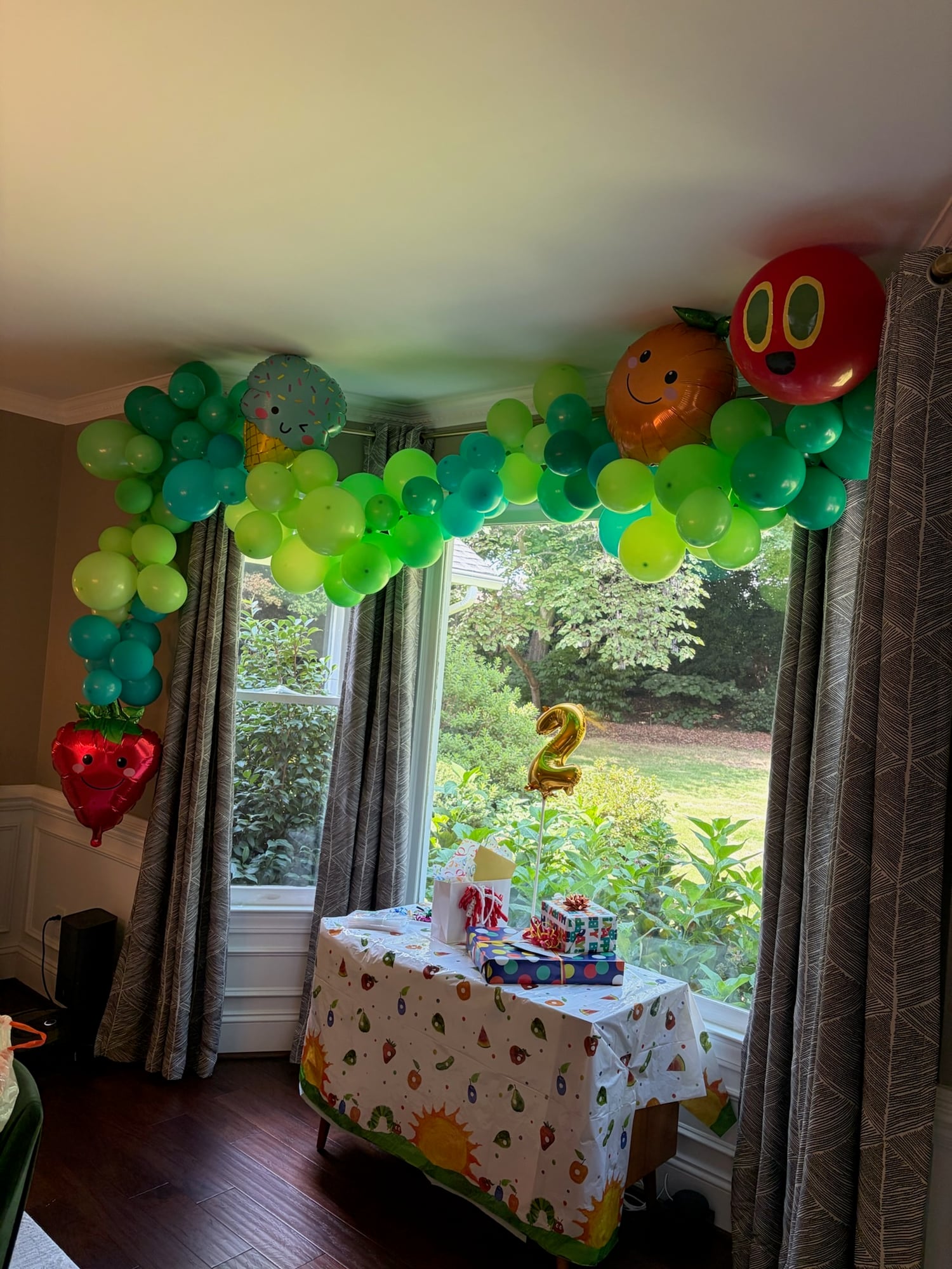 Green caterpillar-themed balloon garland for a second birthday
