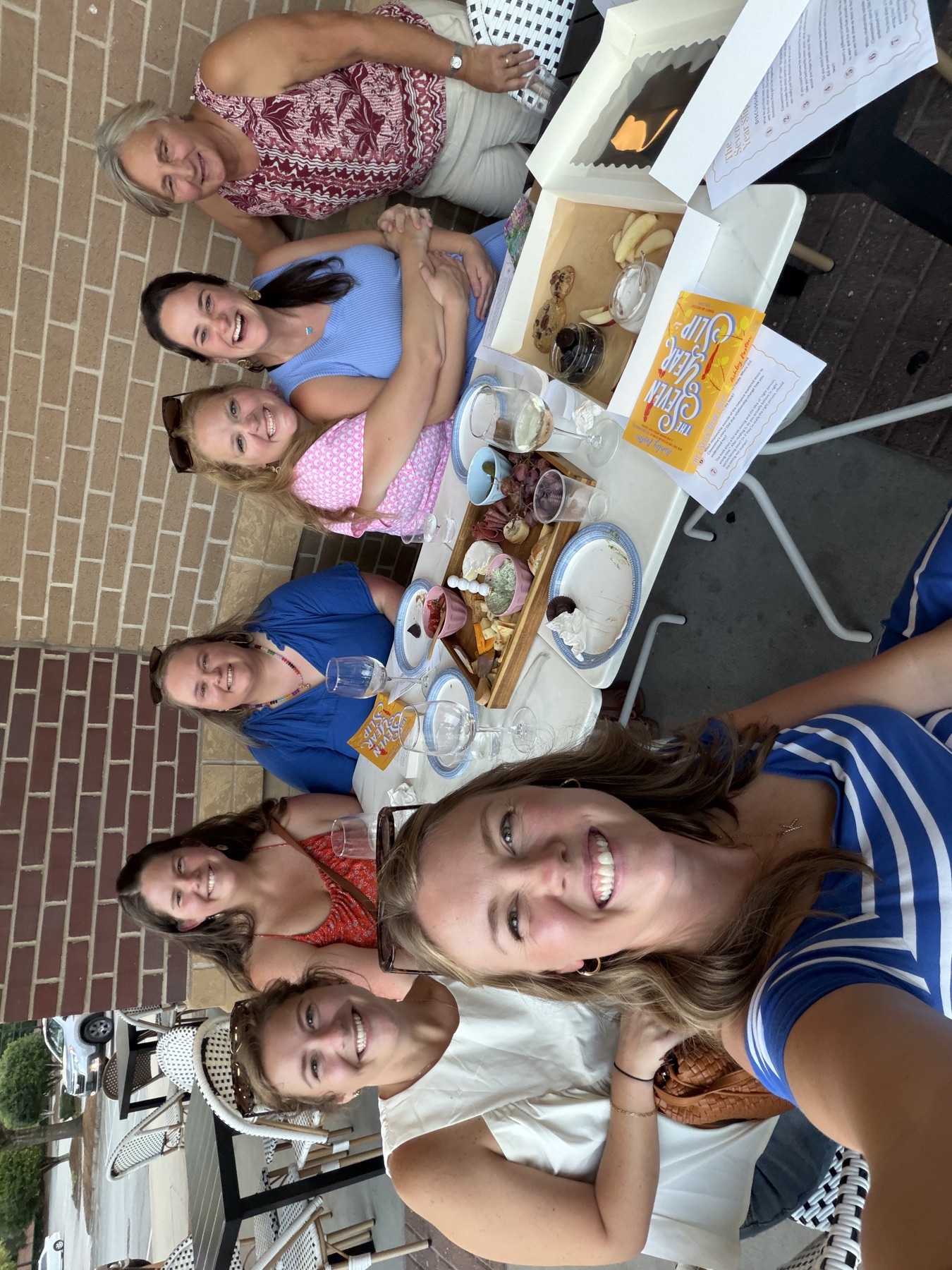 Friends smiling together around the Pink Porch book club table