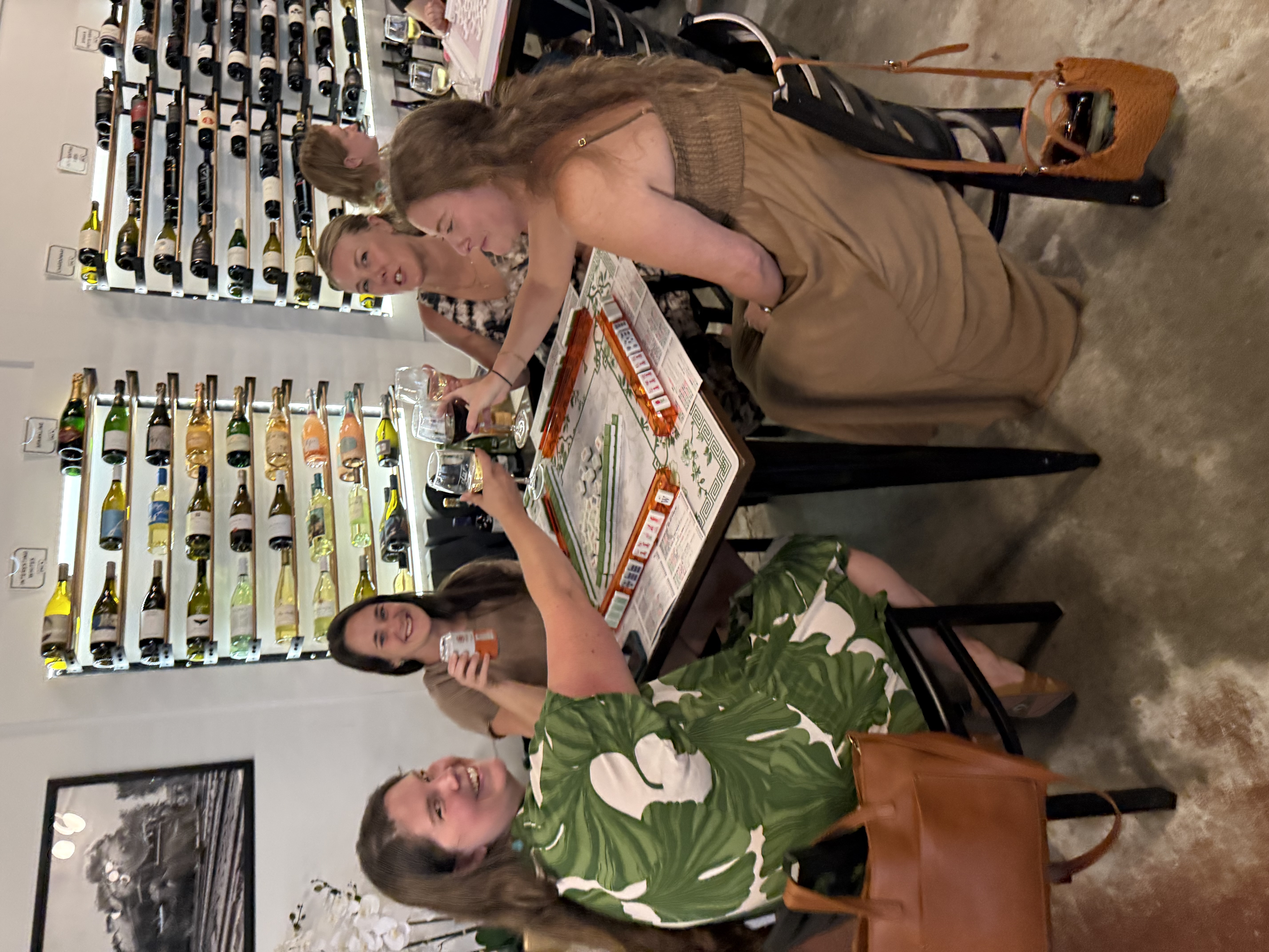 Friends raising their glasses around a Mahjong table