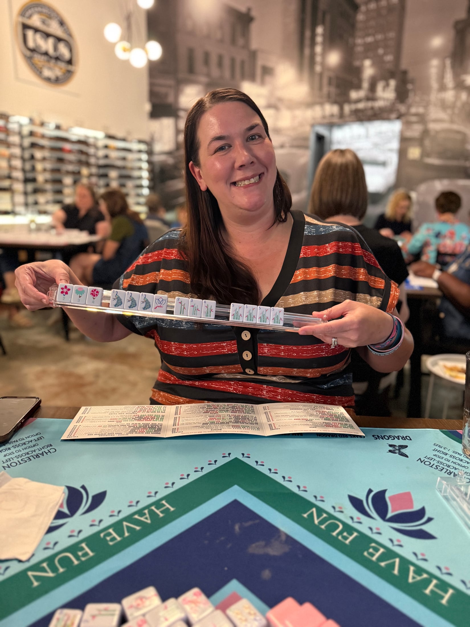 A smiling Mahjong player showing her tile rack